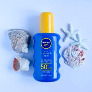 Blue Nivea Sun SPF 50+ sunscreen bottle on white background with seashells and starfish for summer skincare.