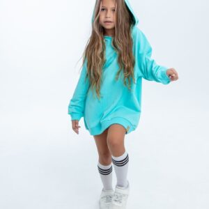 Portrait of a stylish child in a blue hoodie and white sneakers against a white background.