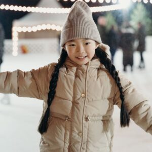 A cheerful young girl with braided hair enjoys ice skating outdoors during winter.