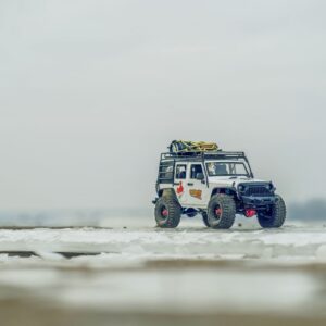 Close-up of a miniature off-road toy vehicle on a snowy landscape, highlighting adventure and exploration themes.