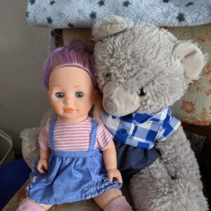 a doll and a teddy bear sitting next to each other
