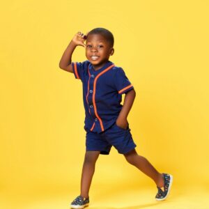Young boy in baseball outfit on yellow background