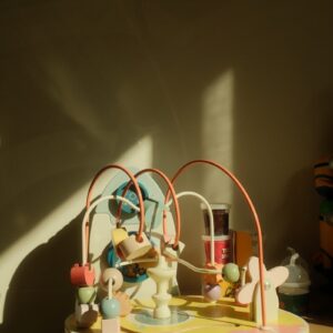 A colorful wooden bead maze toy bathed in sunlight.