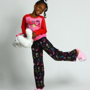 girl in pink and white long sleeve shirt and blue pants holding white plush toy