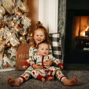 girl in red and white plaid pants sitting on floor beside brown and white floral sofa