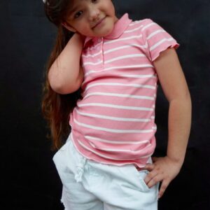 A little girl in a pink shirt and white shorts
