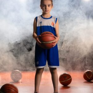 a young boy holding a basketball standing in front of three basketballs